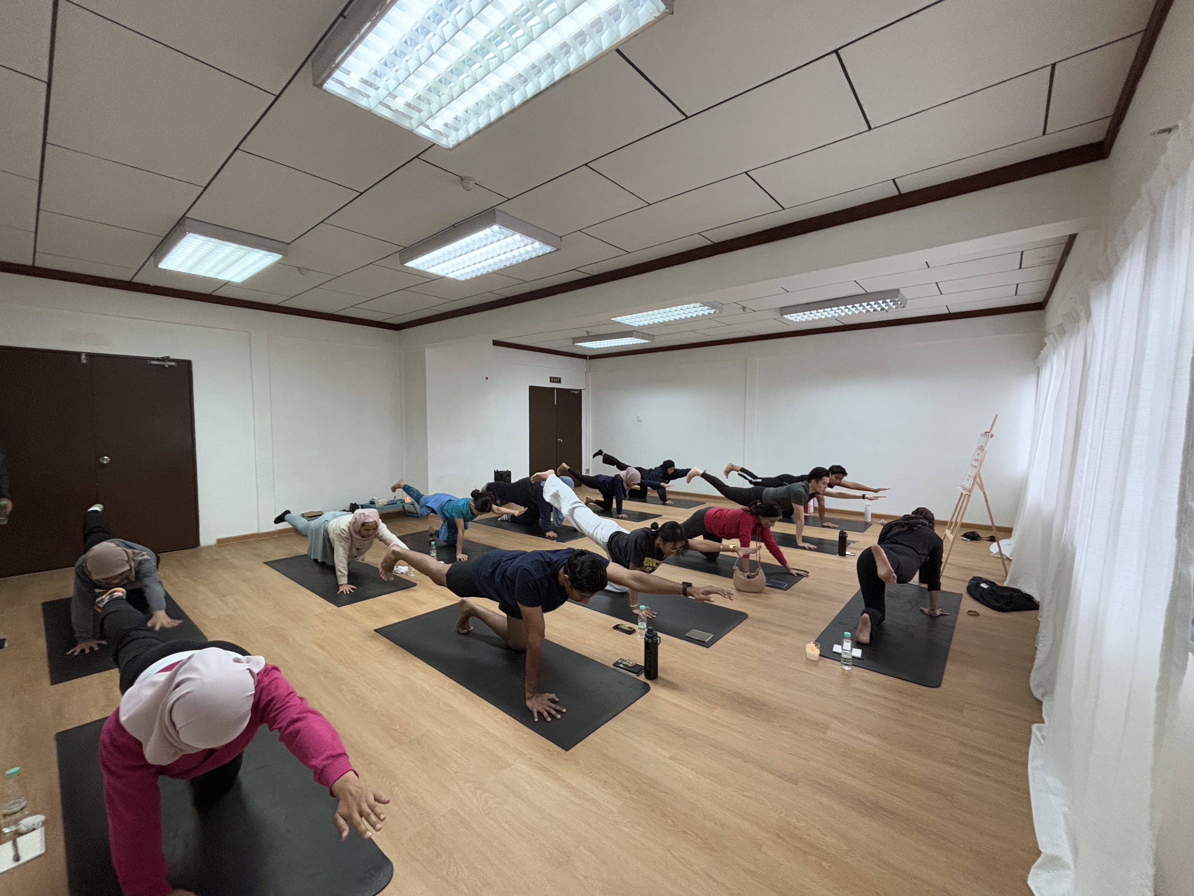 Guests moving through a balance pose on mats during a session of the January 2025 Yoga Retreat at The Cool Point Hotel